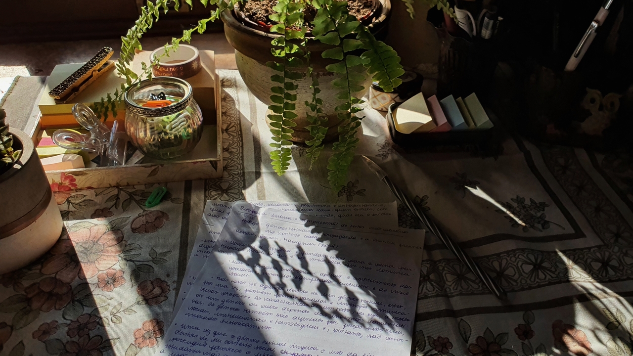 Notas da aula Leitura e compreensão de textos não literários sobre uma mesa com uma faixa de sol e plantas e itens de papelaria ao redor